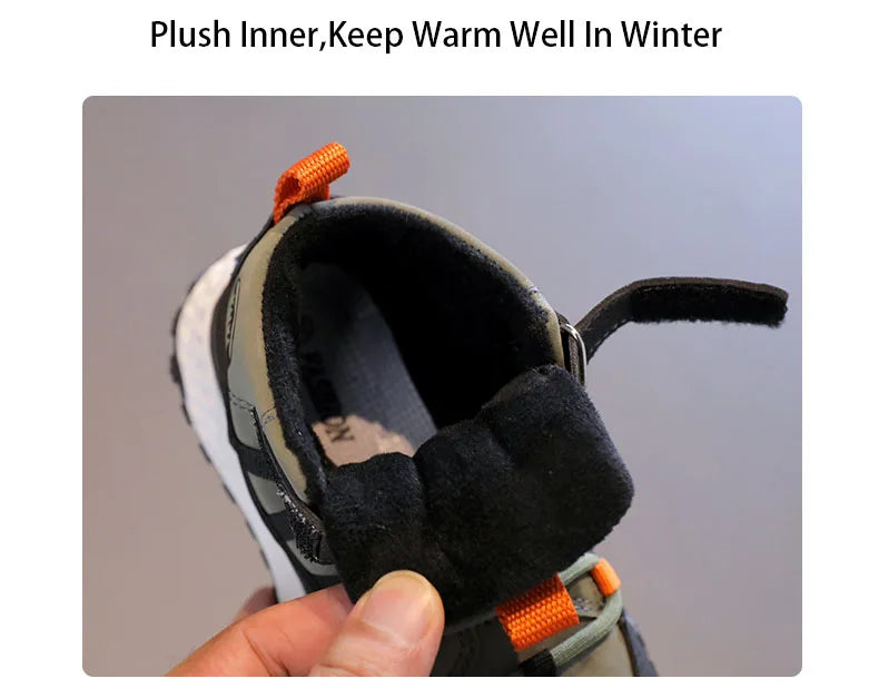 A close-up of a child's winter boot with a thick black plush inner lining being held by a hand, featuring a gray and black upper with bright orange pull tabs, under the text 'Plush Inner, Keep Warm Well In Winter'.