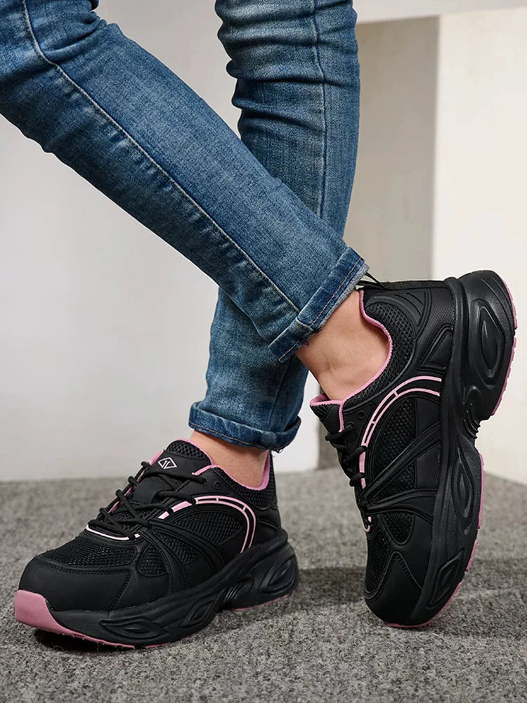 Black chunky platform sneakers with pink accents, shown on a model wearing blue jeans.
