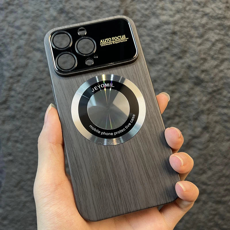 iPhone case with a wooden texture and metal ring holder held by a hand against a gray background