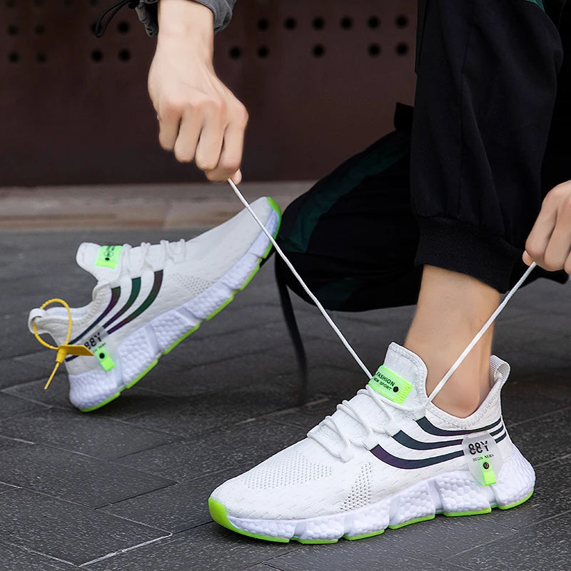 Person tying white sneakers with green accents on a dark floor.