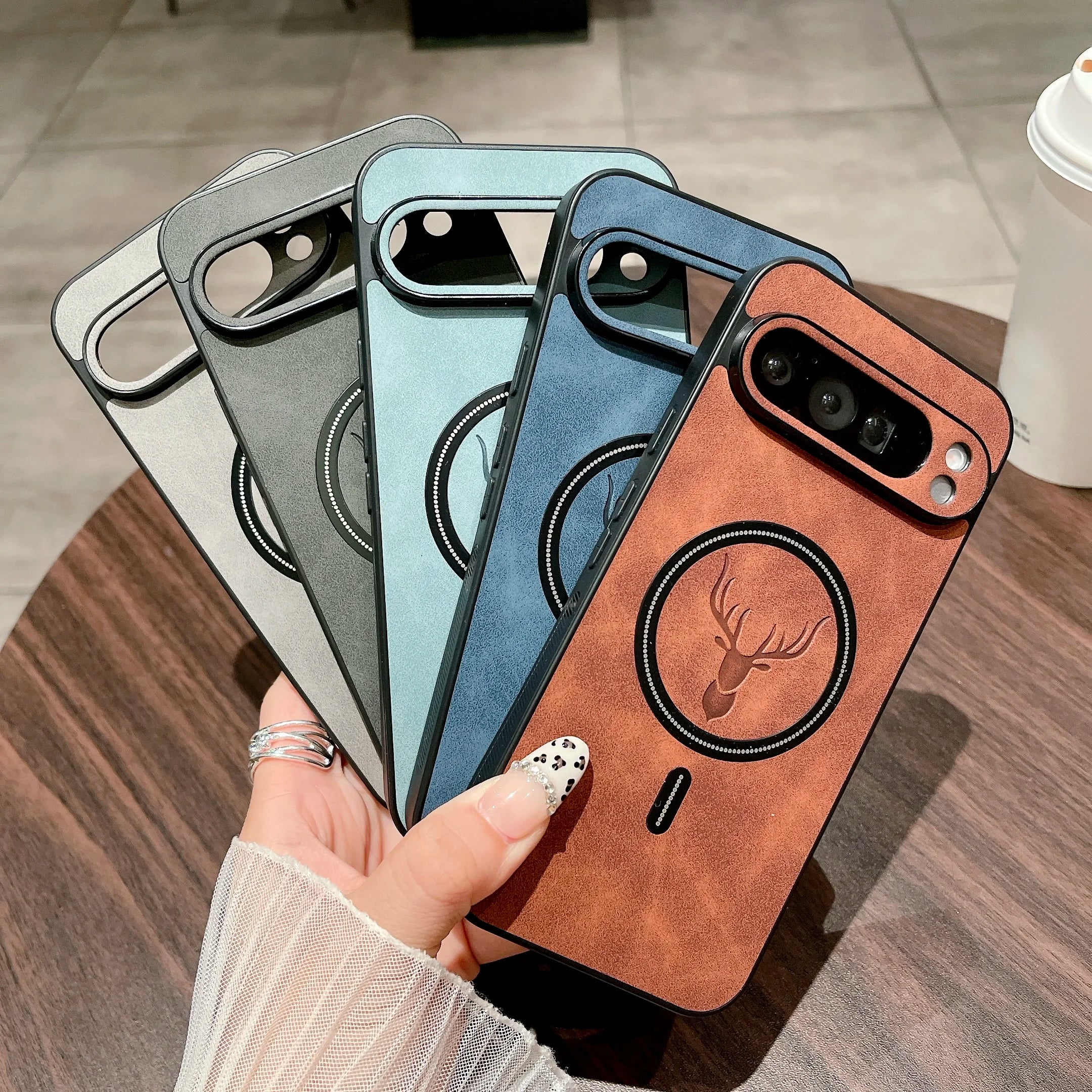 Four Leather Magnetic Cases for Pixel in different colors held by a hand on a wooden surface.