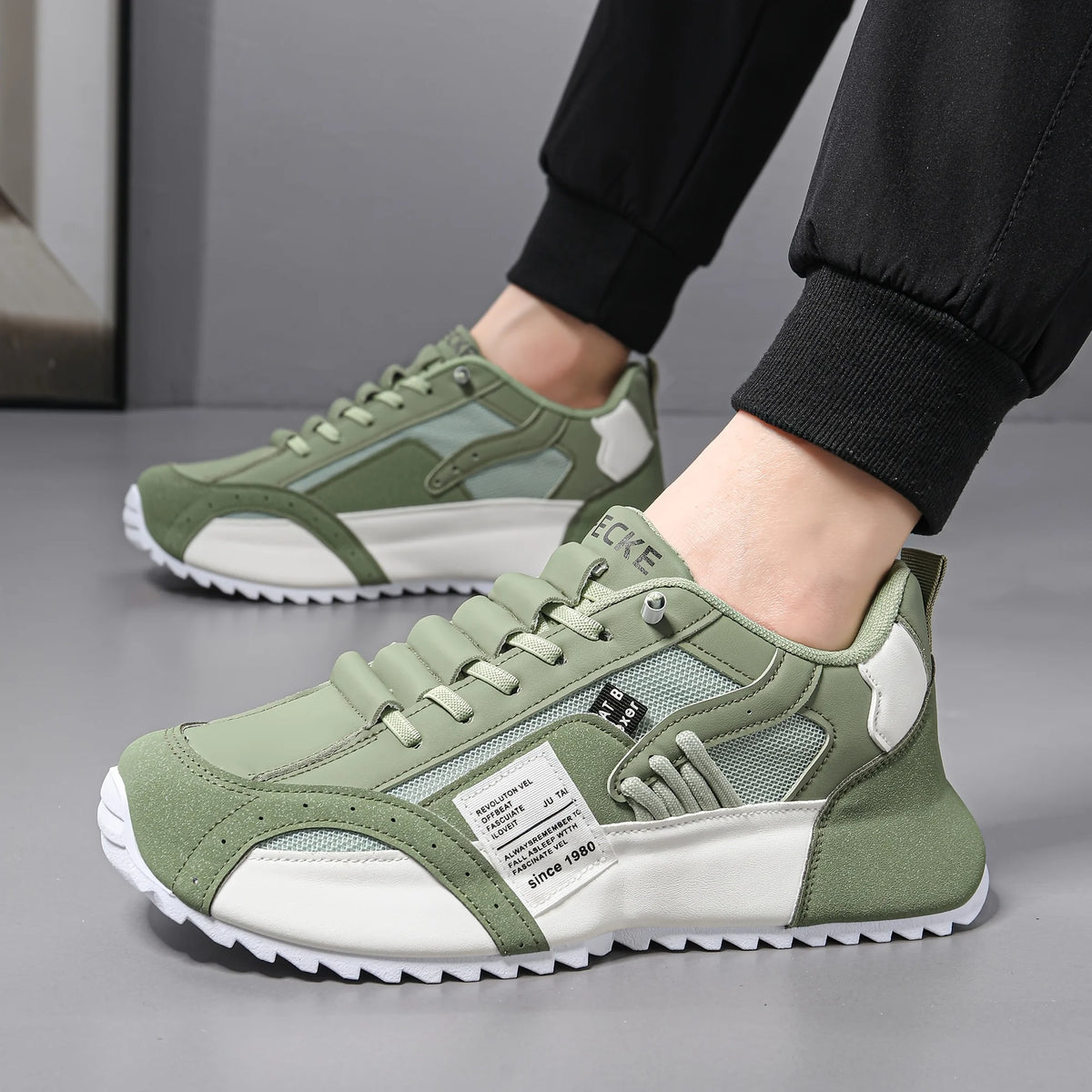 Green and white sneakers worn by a person on a gray floor.
