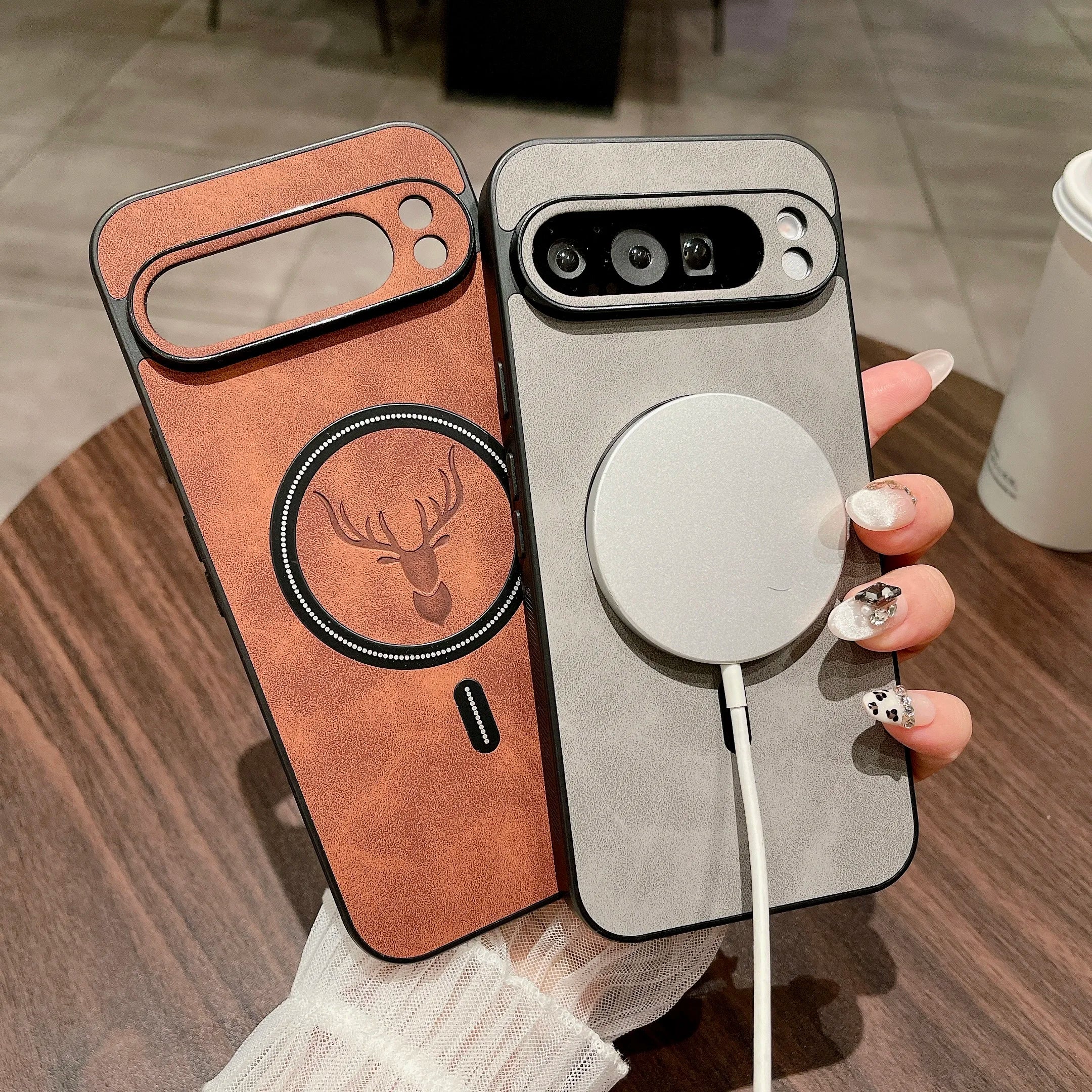 Two phone cases with different designs held by a hand on a wooden surface.