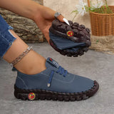 Blue shoe with brown sole held by a hand, with a blurred background