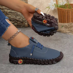 Blue shoe with brown sole held by a hand, with a blurred background