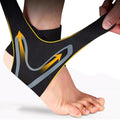 Person wearing a black ankle support brace with yellow and gray design on a white background