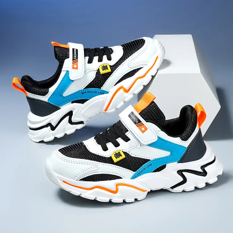 Pair of children's sneakers with black, white, blue, and orange design on a gray background