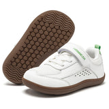 White toddler's low-top casual shoe with a hook-and-loop strap and brown sole, shown alongside its brown textured outsole on a white background.